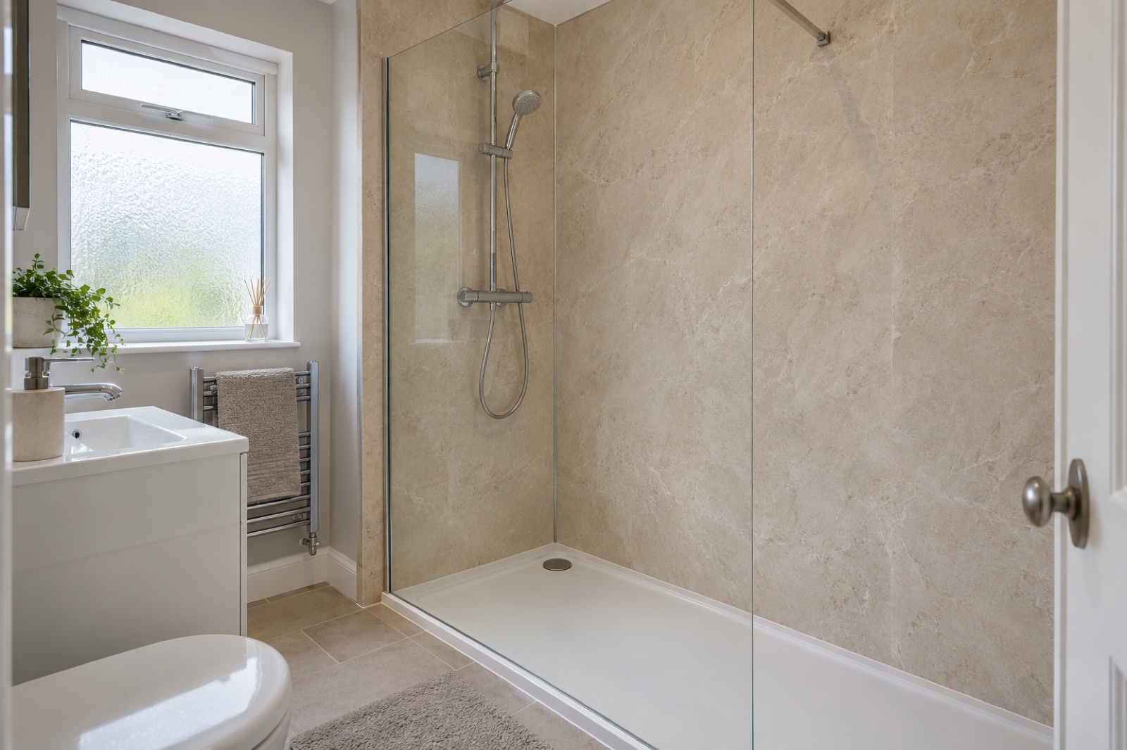 Pale stone-effect bathroom wall panels around a walk-in shower with a glass screen, chrome fittings and white tray